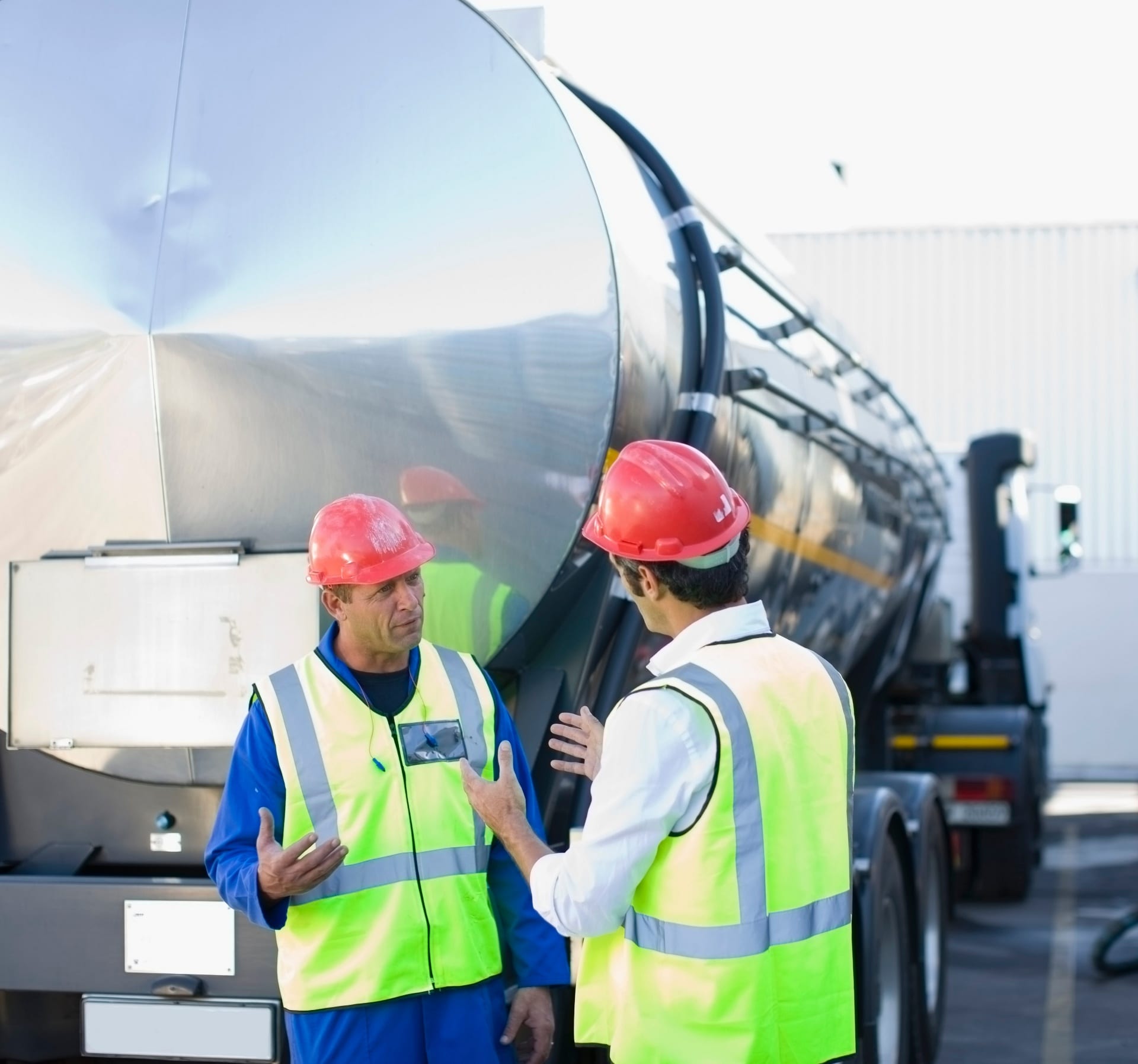 Brightline crew and shipper discussing operations beside a stainless bulk tank trailer